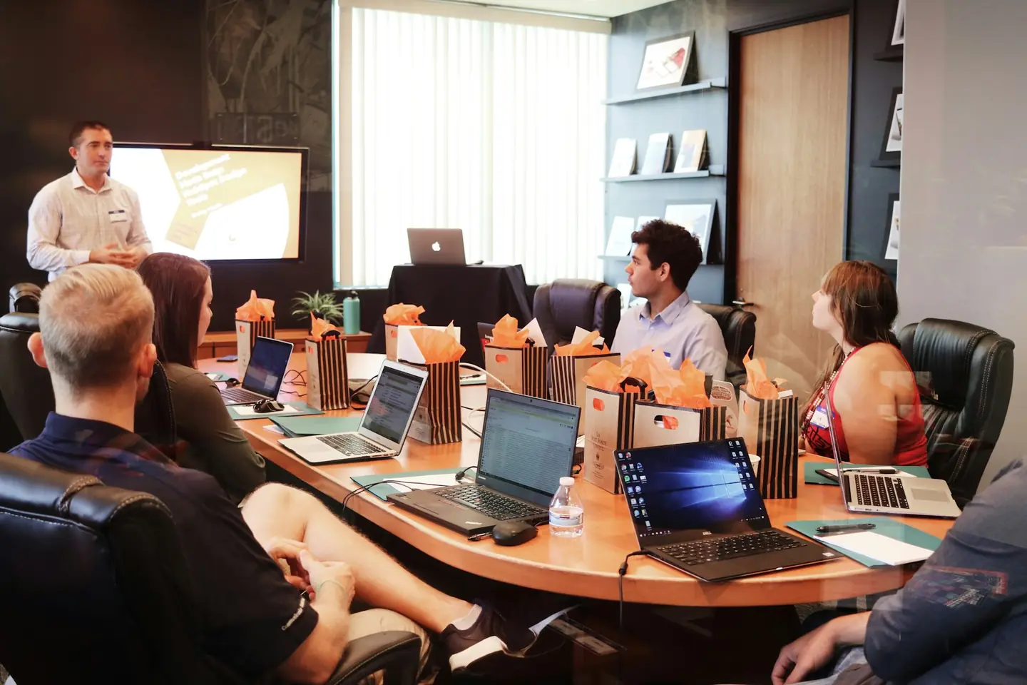 Marketing team meeting around a long conference table with laptops